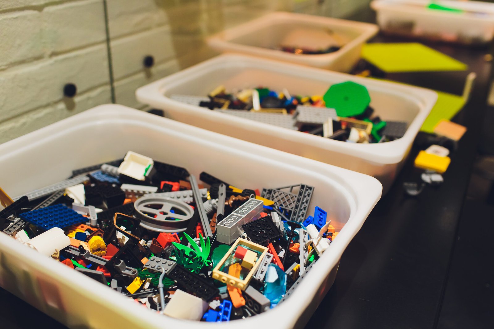 Large plastic bins filled with organised Lego pieces in a play area.