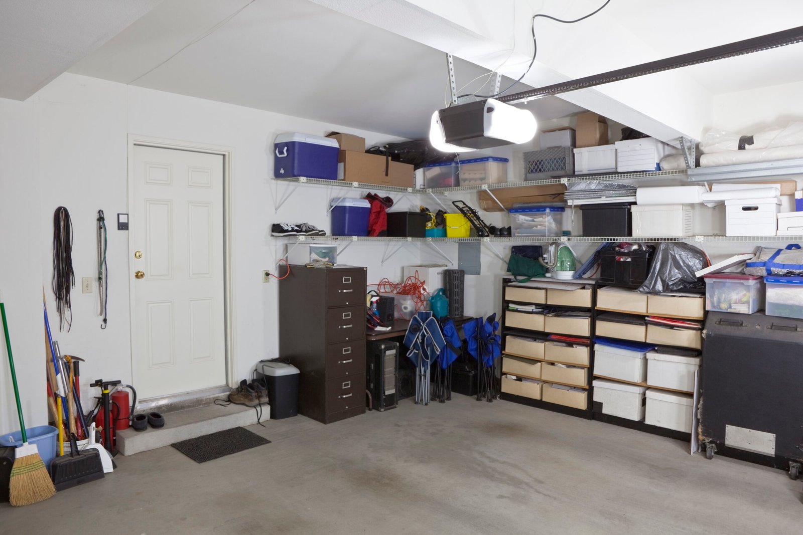 Organised garage storage with wall shelving, plastic storage bins, and clear floor space