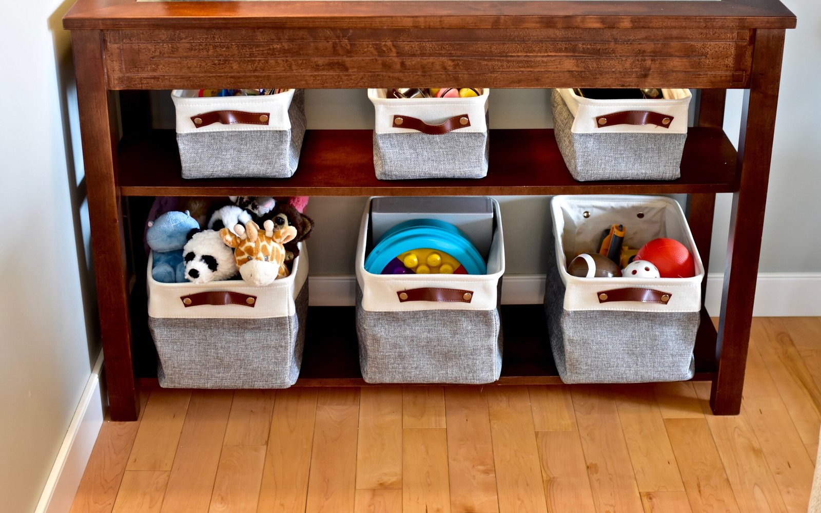 Toy storage bins under console table in a small living room